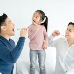 Happy family cleaning teeth with toothbrushes together